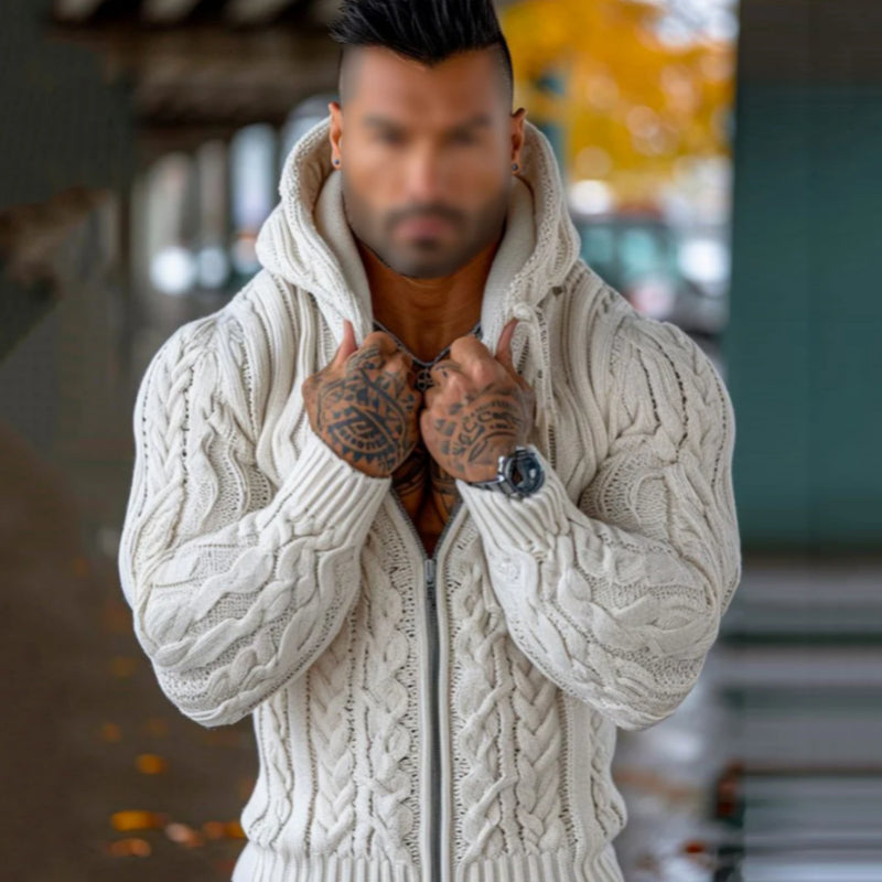Person wearing a white cable knit sweater with a blurred background