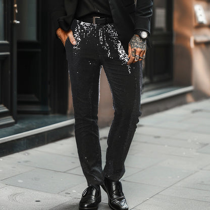 Person wearing black sequin pants and black shoes on a city street.