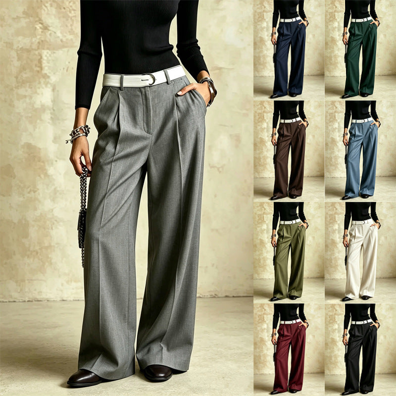 A model wears gray wide-leg pleated trousers with a white belt, shown against a textured beige studio background. A vertical column on the right shows the same pants in multiple color options: navy, green, brown, blue, black, olive, cream, burgundy, and black.