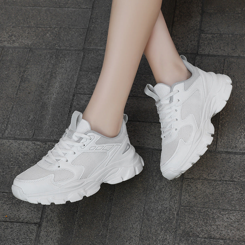 White sneakers worn on a dark tiled floor