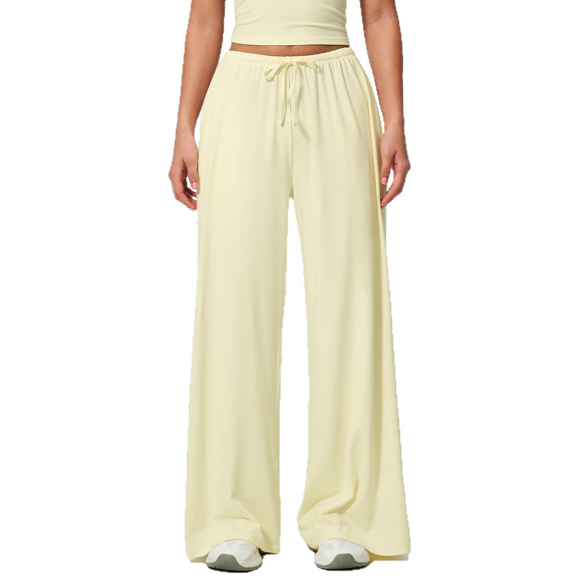 Person wearing light yellow wide-leg pants on a white background