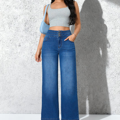 A model wearing blue wide-leg denim jeans with a light gray crop top and a light blue shoulder bag, standing against a textured gray wall with a strong shadow.